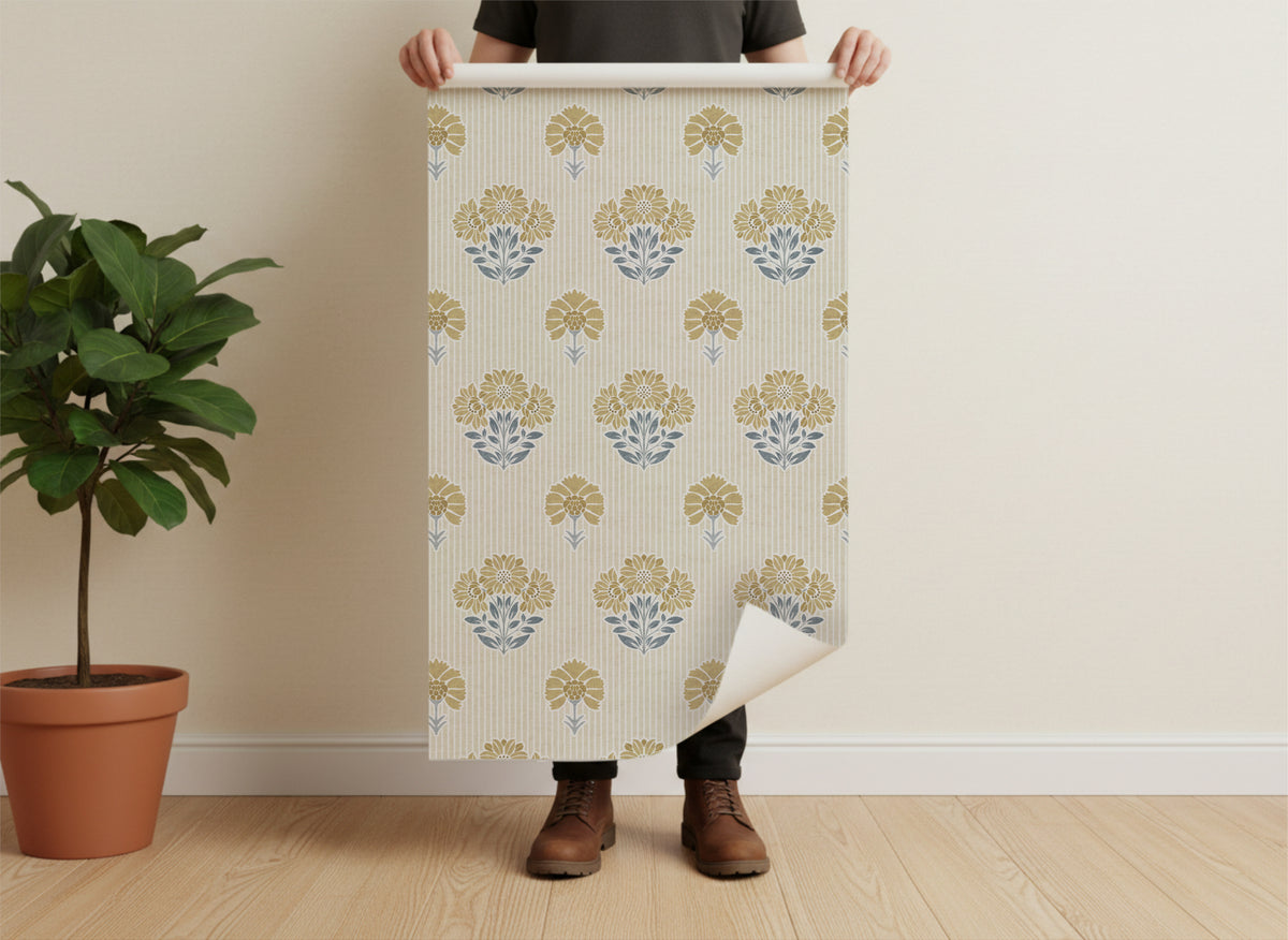 Person holding a roll of vintage floral-patterned wallpaper against a plain wall.