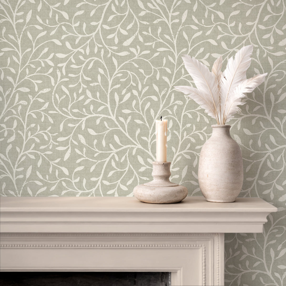 Botanical print wallpaper in sage green styled on fireplace mantel with white ceramic vases and candle