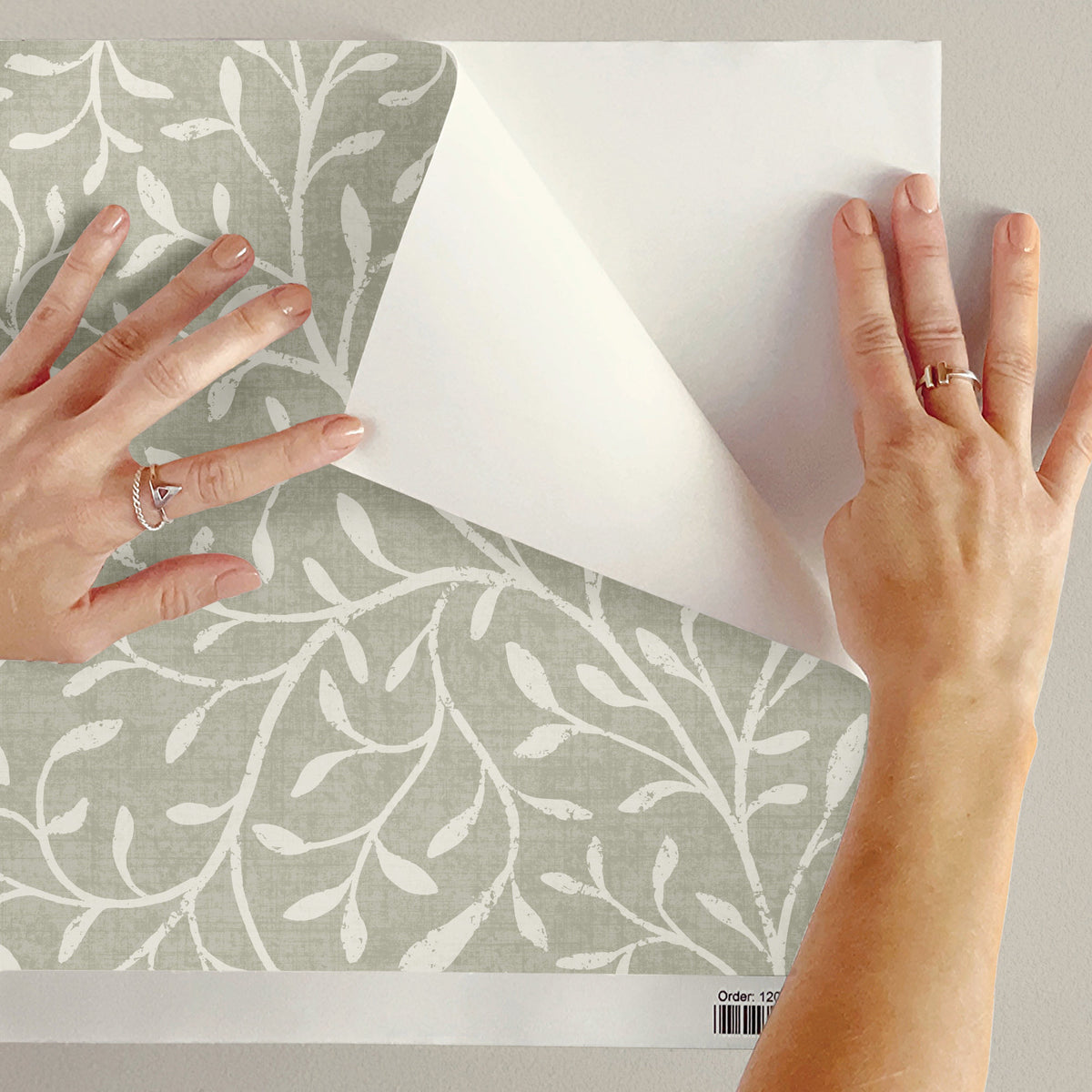 Peel and stick botanical wallpaper close up showing self-adhesive backing being peeled