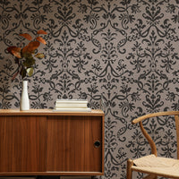 Vintage style study with brown Victorian damask wallpaper, wooden desk, and autumnal decor.