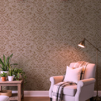 Contemporary living room with golden tan Victorian damask wallpaper, white armchair, and potted plant.
