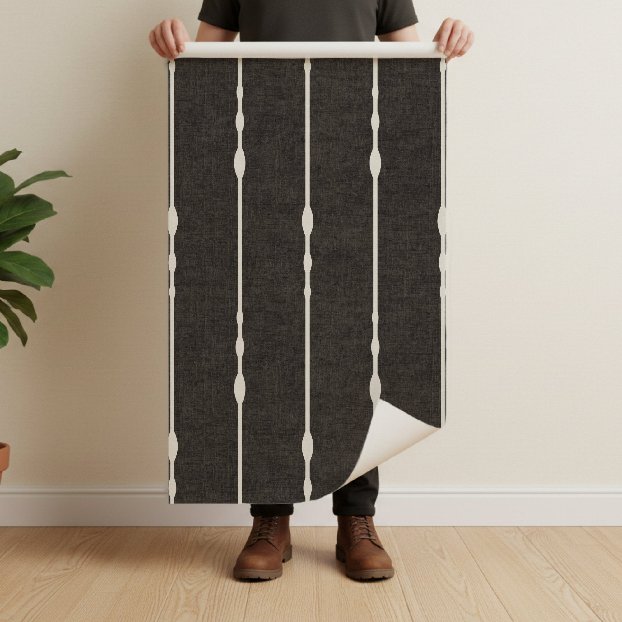 Vertical striped wallpaper roll in Black and White held against neutral background