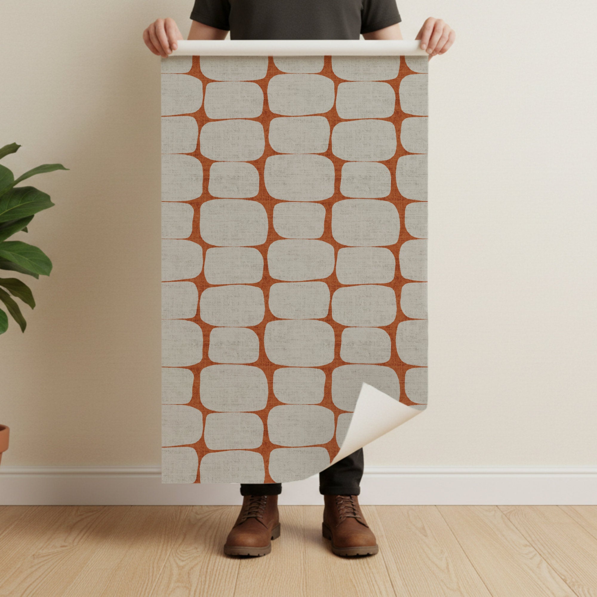 Person holding a large wallpaper swatch with a mid centrury modern geometric pattern