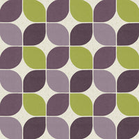 A top-down flat lay featuring a sample of the plum and wabisabi green geometric wallpaper. The sample is styled with interior design elements to show how the MCM colours coordinate with modern textures.