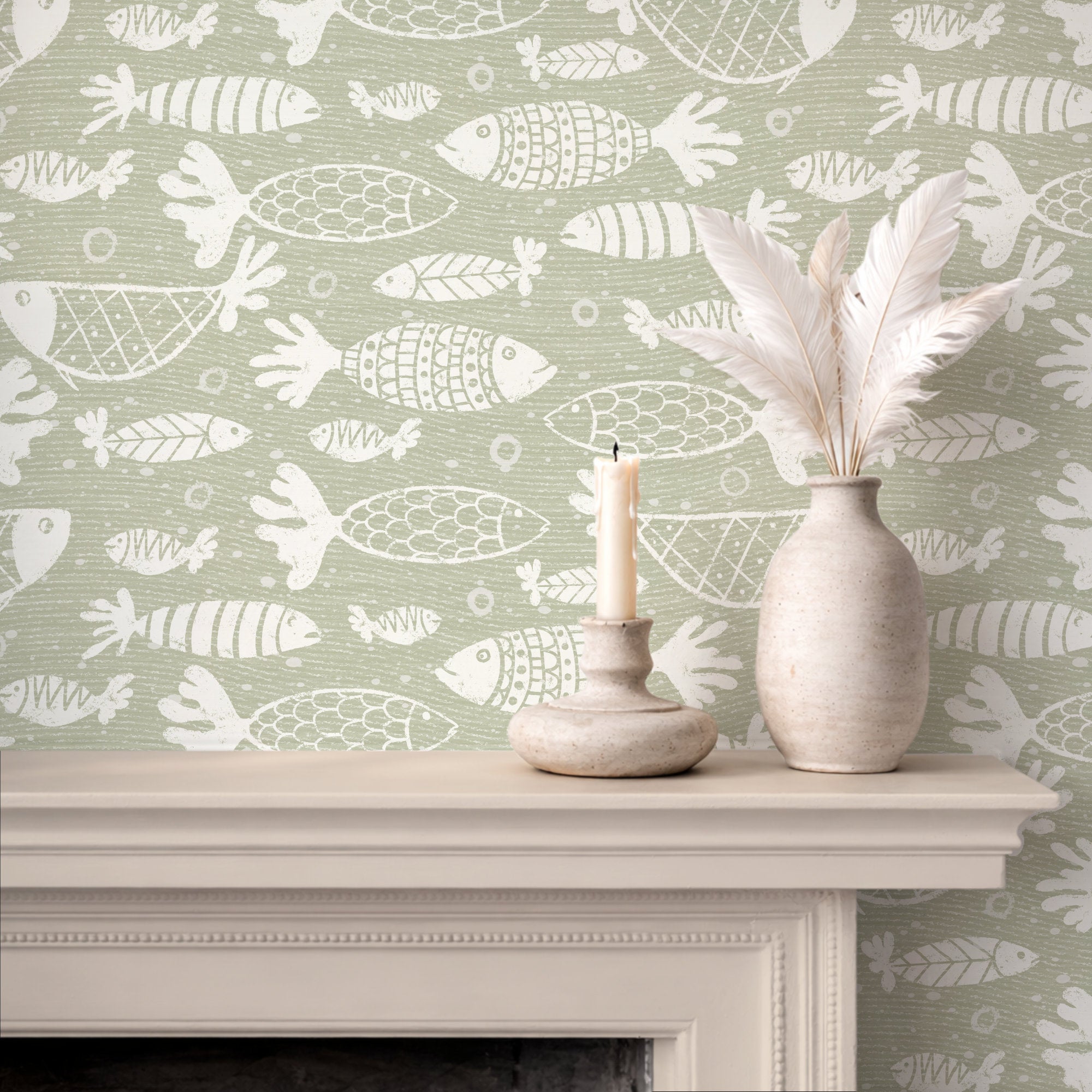 A styled interior scene showing a fireplace mantel with a patterned green and white school of fish wallpaper, a white feather vase, and a candle holder with a lit candle.