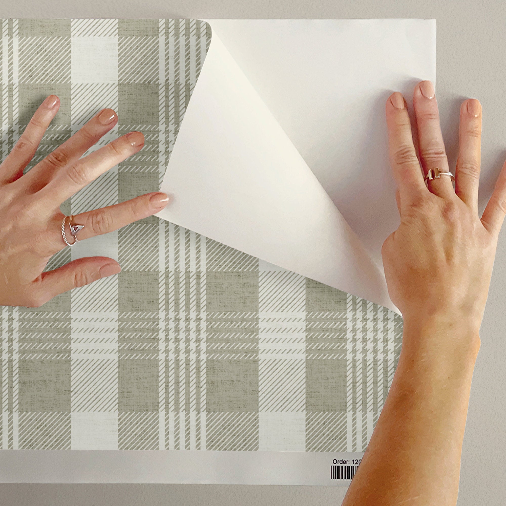 Peel and stick plaid wallpaper being peeled from wall during installation